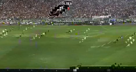 Jogadores em campo durante partida de futebol no estádio.