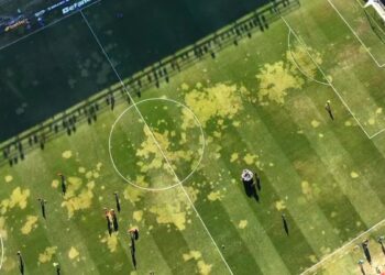 Gramado de futebol com manchas de óleo no campo.