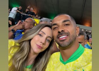 Celebridade usando camiseta do Brasil, torcendo no estádio.