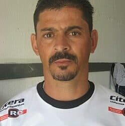 Jogador de futebol vestindo uniforme branco com detalhes pretos.