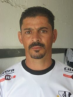 Jogador de futebol vestindo uniforme branco com detalhes pretos.