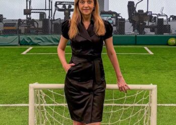 Pessoa posando no campo de futebol com mini golinho.