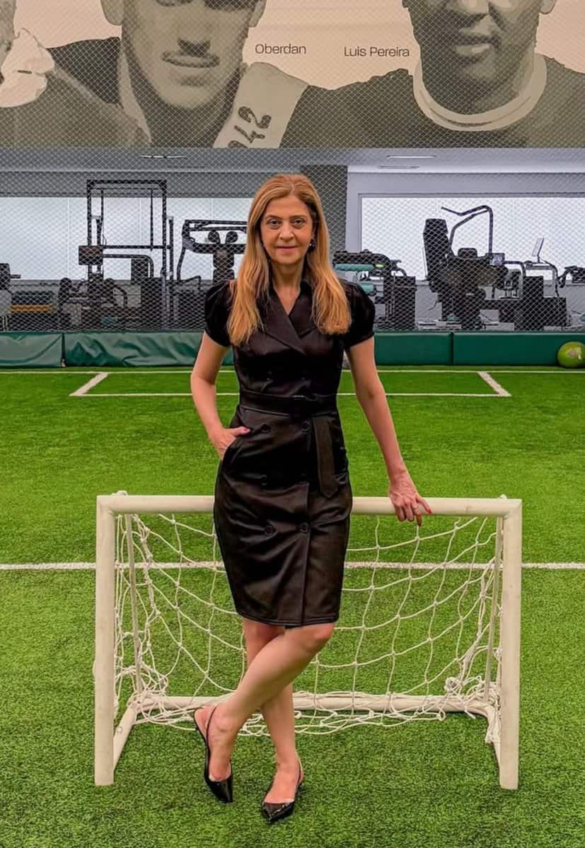 Pessoa posando no campo de futebol com mini golinho.