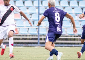 Jogador do Vasco driblando na partida de futebol.