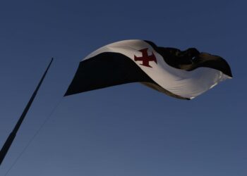 Vasco da Gama com bandeira ao vento em céu claro.