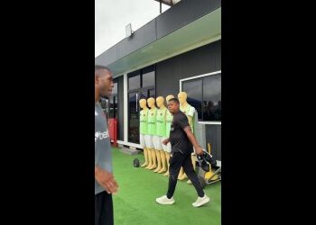 Jogador de futebol na frente de manequins de treino.