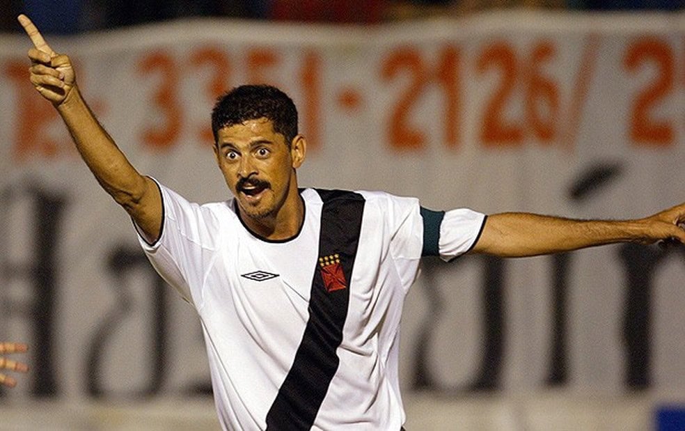 Jogador comemorando gol com braços abertos e expressão emocionante.