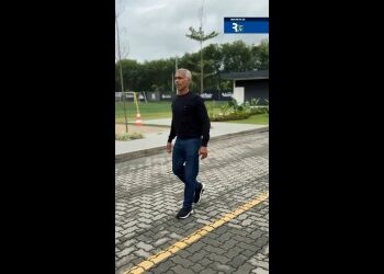 Homem caminhando na rua com céu nublado.