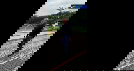 Homem caminhando na rua com céu nublado.