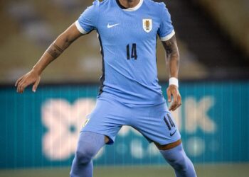 14 jogador com uniforme azul, chuteira roxa, jogando futebol.