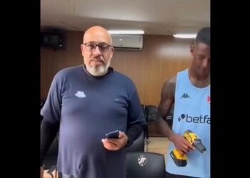 Homem com óculos segurando celular.