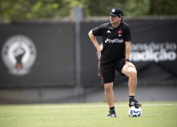 Jogador de futebol treinando com bola no campo.