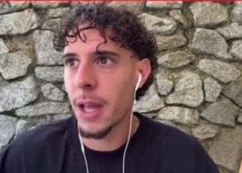 Jovem com cabelo cacheado falando ao celular.