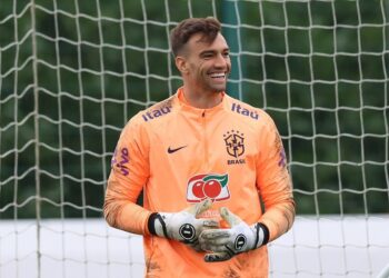ALT: Goleiro do Brasil sorrindo em campo de futebol.