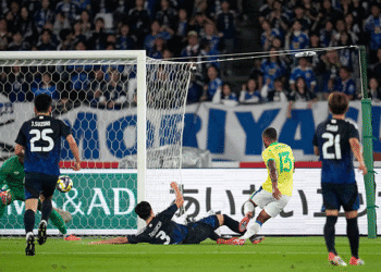 Goleiro e atacante em ação de jogo de futebol.