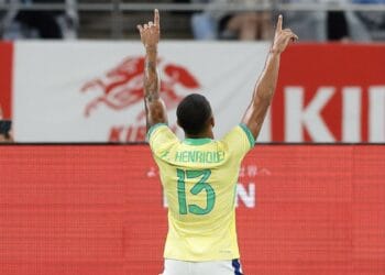 Jogador de futebol comemorando com braços erguidos.