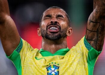 Aterrizado: jogador do Brasil com expressão emotiva, braços levantados, usando uniforme amarelo e verde.