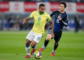 Jogador brasileiro com uniforme amarelo e branco em partida contra jogador coreano.