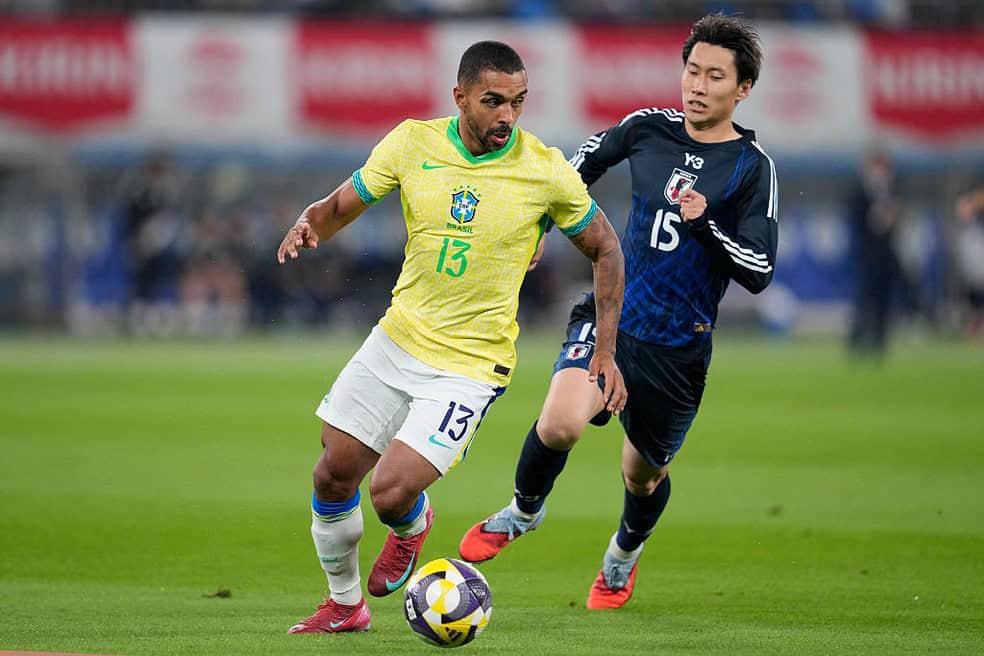 Jogador brasileiro com uniforme amarelo e branco em partida contra jogador coreano.