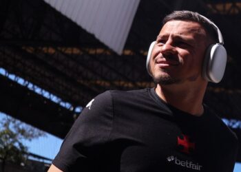 Jogador do Vasco usando fones de ouvido em estádio ao ar livre.