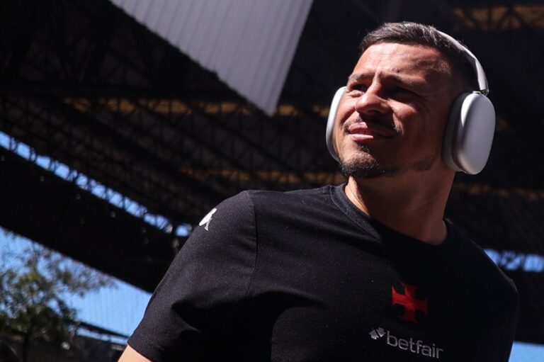 Jogador do Vasco usando fones de ouvido em estádio ao ar livre.
