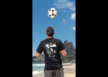 Homem jogando bola na praia com o Cristo Redentor ao fundo.