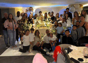 Festa de aniversário com muitas pessoas sorrindo e decoração elegante.