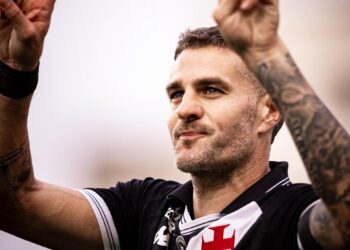 Vasca de jogador de futebol com gesto de vitória.