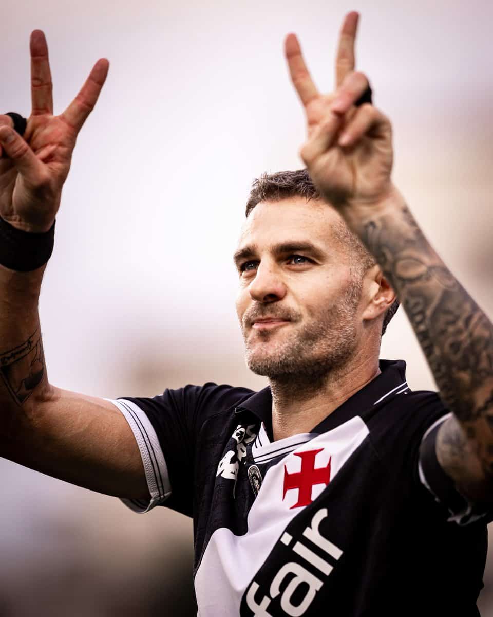 Vasca de jogador de futebol com gesto de vitória.