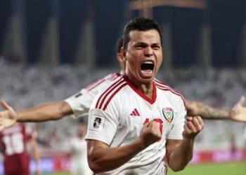 Jogador comemorando com entusiasmo em campo de futebol.