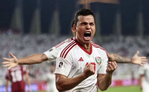 Jogador comemorando com entusiasmo em campo de futebol.