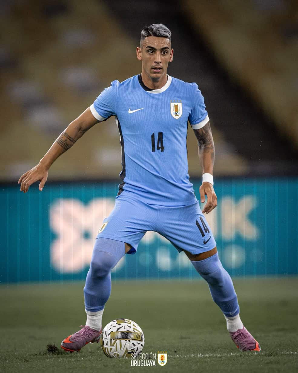 Jugador de futebol uruguayo em campo com uniforme da seleção uruguaia.