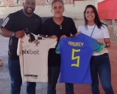 Mario Andrey e duas pessoas segurando camisas de futebol do Vasco.