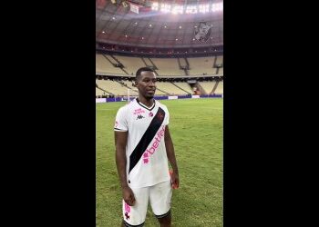 Jogador do Vasco no estádio, camisa branca e calções brancos.