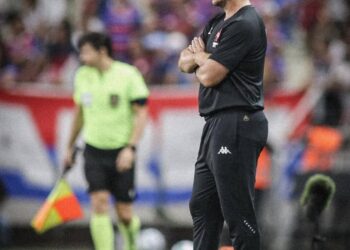 Referee com braços cruzados no campo.