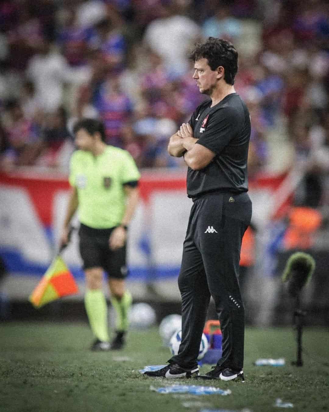Referee com braços cruzados no campo.