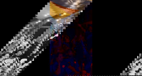 Jovens torcedores do Vasco celebrando em restaurante.