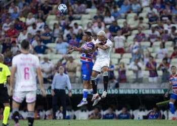 Jogadores de futebol disputando a bola no ar.