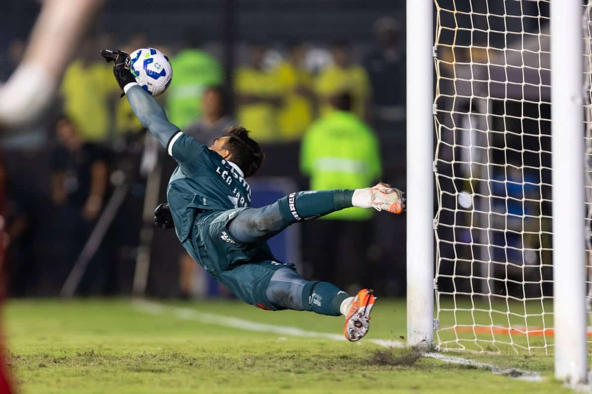 Salto do goleiro do Vasco defendendo chute ao gol.