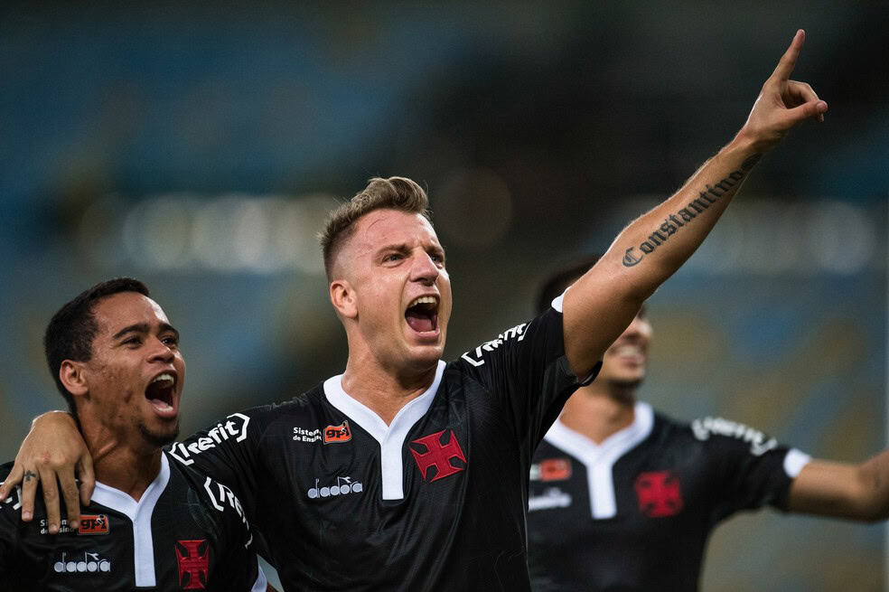 Jogador comemorando gol com amigos no estádio.