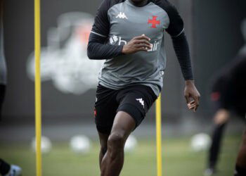 Atleta treinando com cones no campo de futebol.