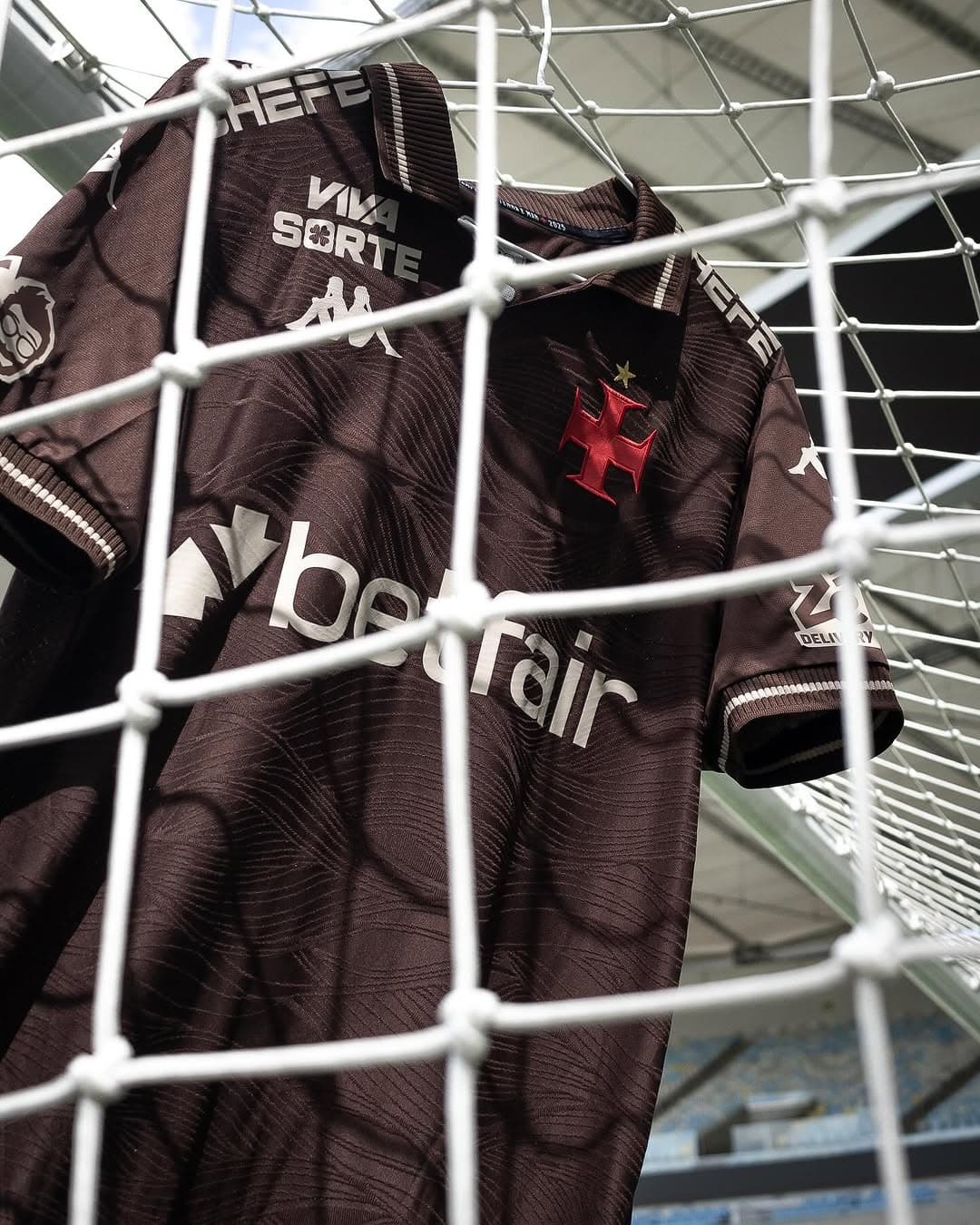 Camisa de futebol do Vasco da Gama no estádio, vista através da rede de proteção.