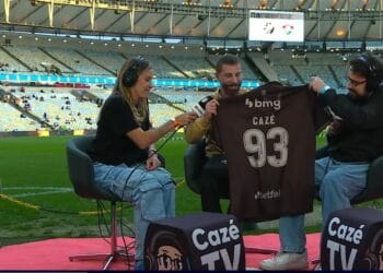A imagem mostra três pessoas em uma entrevista no estádio do Vasco.