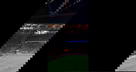 Estádio de futebol lotado durante o jogo.