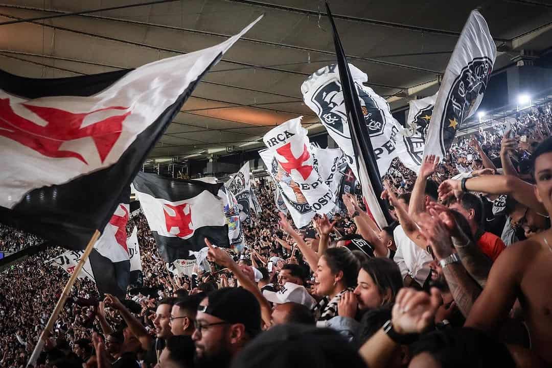 Bandeiras do Vasco sendo agitadas na torcida.