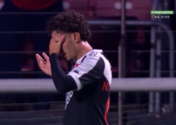 Jogador Vasco com expressão de frustração, cobrindo o rosto com a mão.