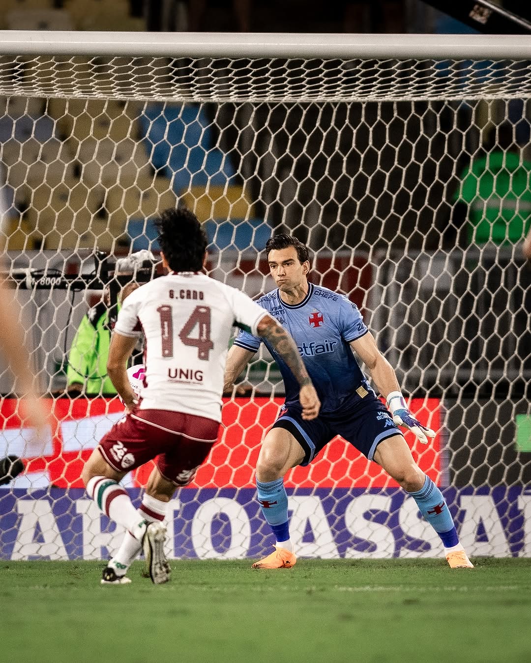 Goleiro do Vasco defendendo chute de atacante do Fluminense.