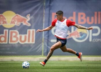 Jogador do Vasco chuta bola em treino no campo.
