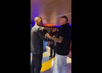Dois homens trocando um aperto de mãos em ambiente interno.