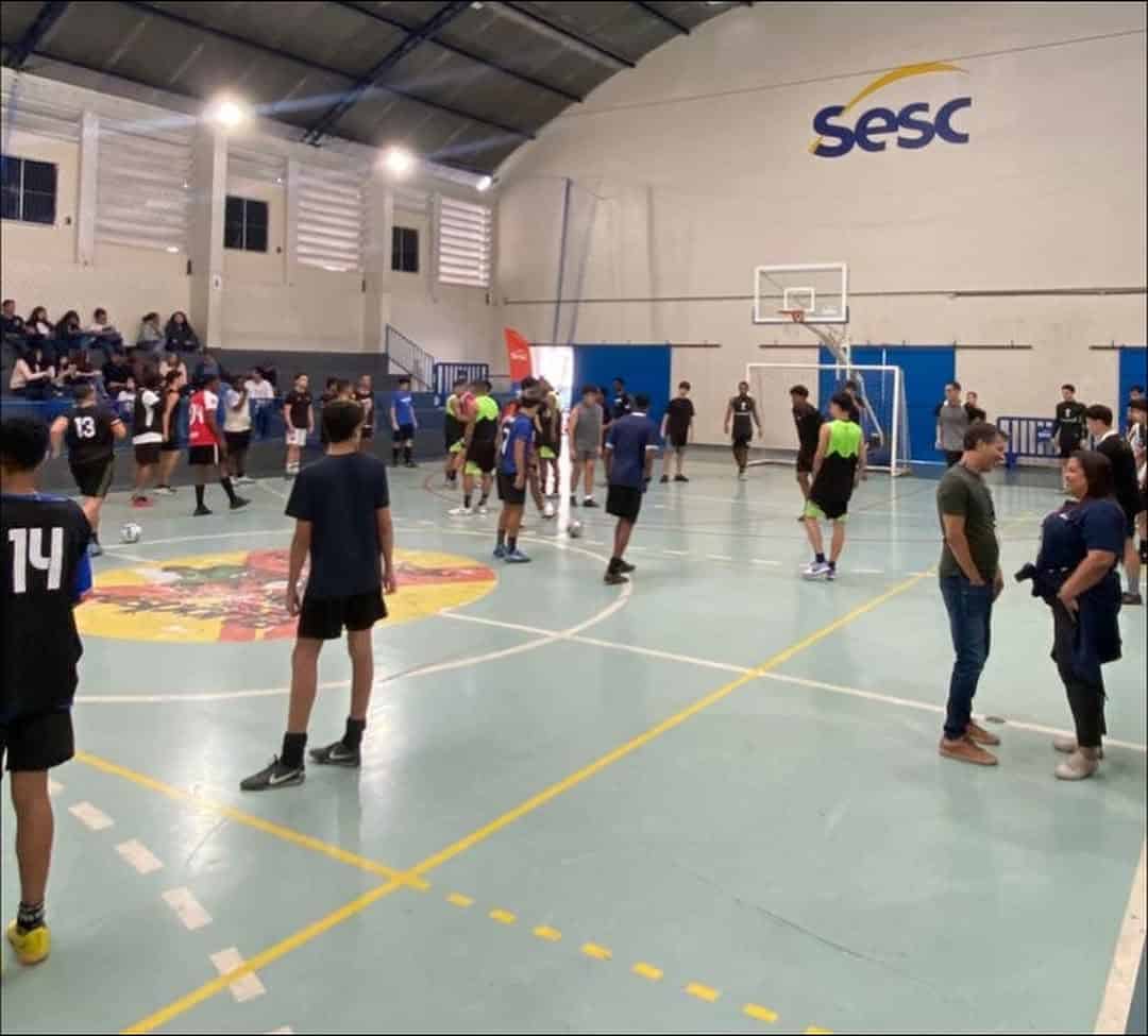 20251022-232642-1-5 Jogadores de futsal em quadra de ginásio coberto.